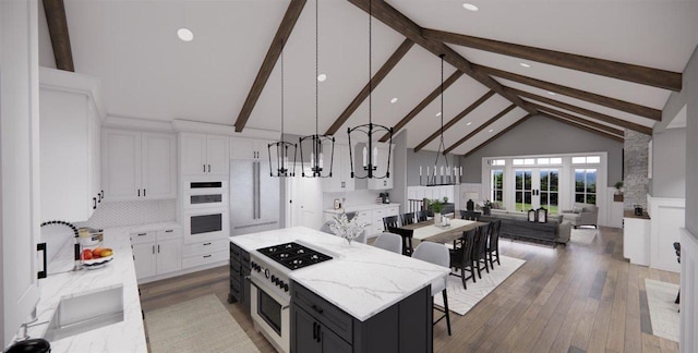 kitchen featuring tasteful backsplash, white cabinets, hanging light fixtures, a center island, and range