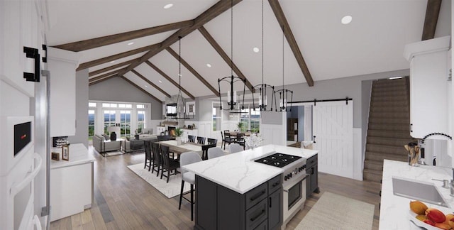 kitchen featuring decorative light fixtures, high vaulted ceiling, stainless steel range, a kitchen island, and a barn door