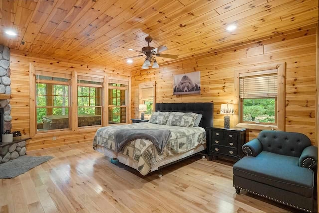 bedroom with ceiling fan, wooden walls, light hardwood / wood-style floors, and wooden ceiling