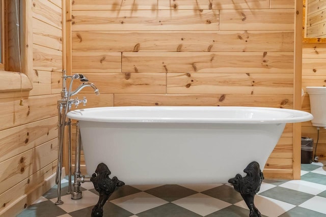 bathroom with a tub and wooden walls