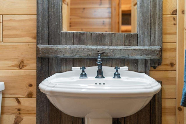 bathroom with sink and wood walls