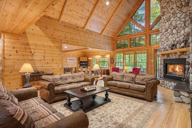 living room featuring a stone fireplace, high vaulted ceiling, wooden ceiling, beamed ceiling, and light hardwood / wood-style floors