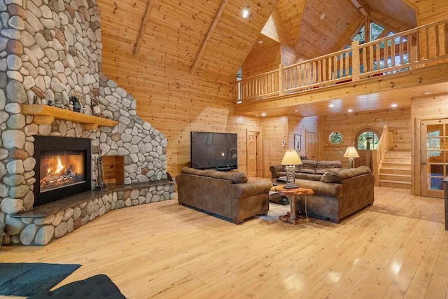 living room with beam ceiling, high vaulted ceiling, a stone fireplace, and wooden ceiling