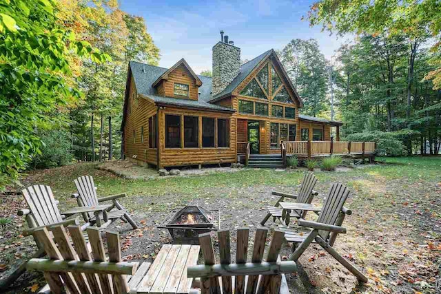 rear view of property featuring a fire pit and a deck