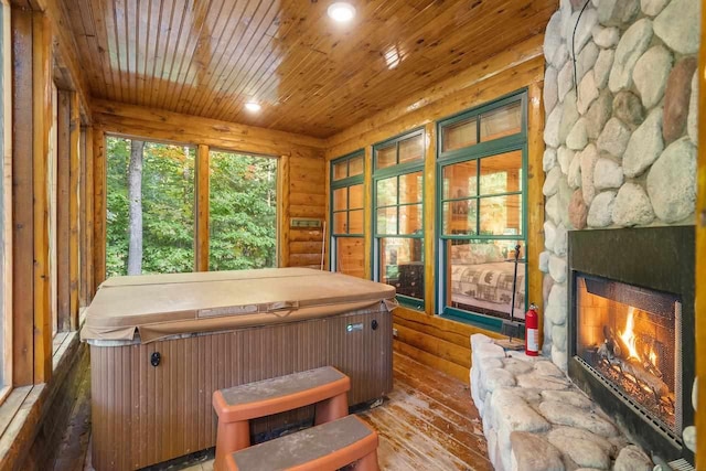 interior space with dark hardwood / wood-style floors, a hot tub, log walls, and a stone fireplace