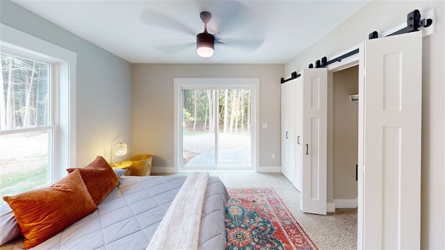 bedroom featuring access to outside, a barn door, and ceiling fan