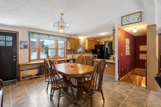 tiled dining room featuring lofted ceiling, sink, and a textured ceiling