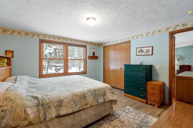 bedroom with a textured ceiling, light hardwood / wood-style floors, and a closet