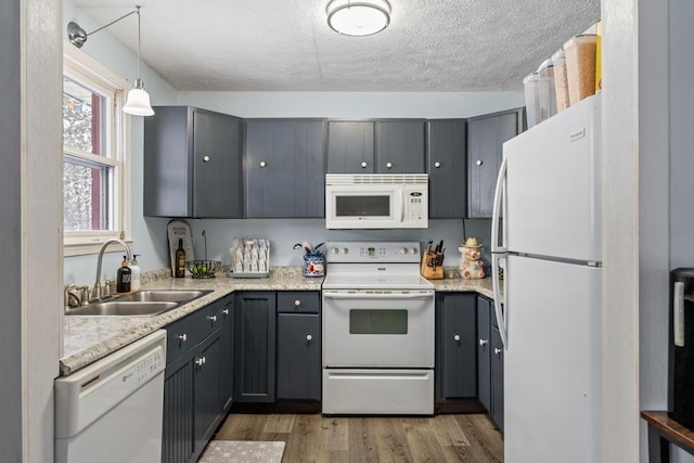 kitchen featuring sink, white appliances, light hardwood / wood-style flooring, gray cabinetry, and decorative light fixtures