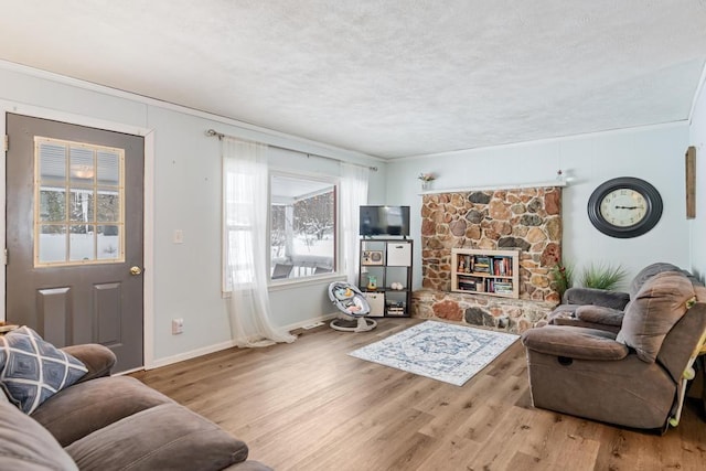 living room featuring a stone fireplace, a textured ceiling, and light wood-type flooring