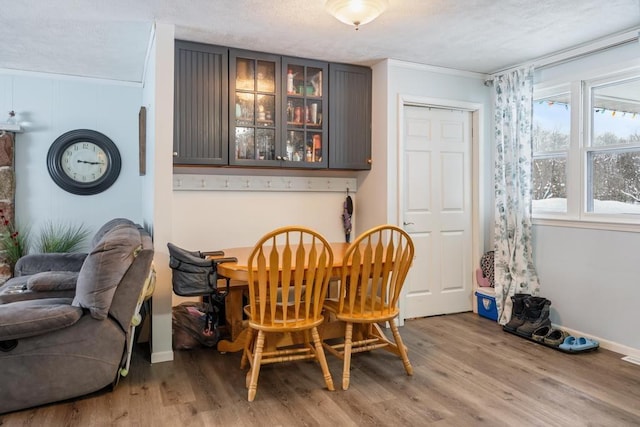 dining room with crown molding, a textured ceiling, and light wood-type flooring