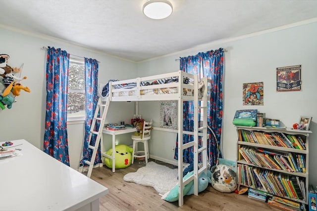 bedroom featuring ornamental molding and light hardwood / wood-style flooring