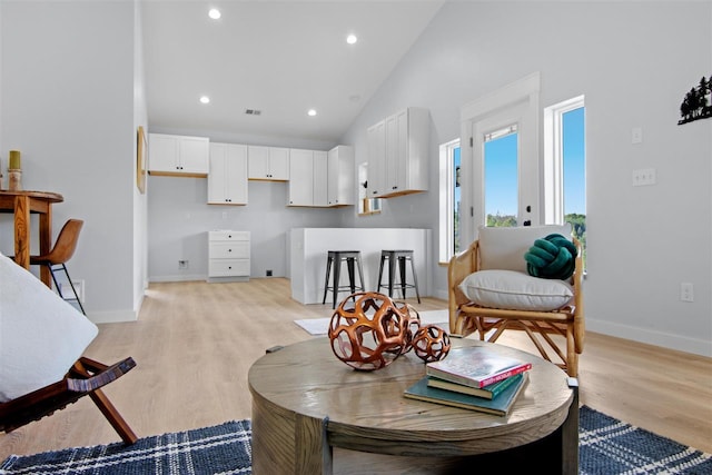 living room featuring high vaulted ceiling and light wood-type flooring