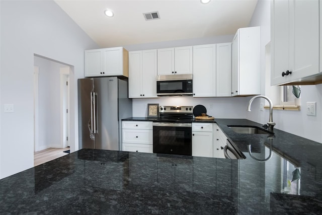 kitchen with white cabinetry, sink, stainless steel appliances, and dark stone countertops