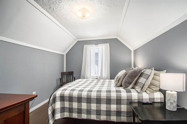 bedroom with vaulted ceiling, hardwood / wood-style floors, and a textured ceiling