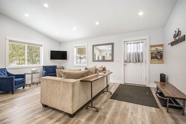 living room with light hardwood / wood-style flooring, vaulted ceiling, and plenty of natural light