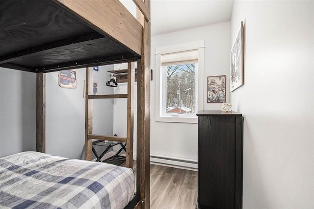 bedroom with hardwood / wood-style flooring and a baseboard heating unit