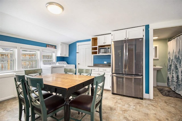 kitchen with sink, white cabinetry, separate washer and dryer, vaulted ceiling, and appliances with stainless steel finishes