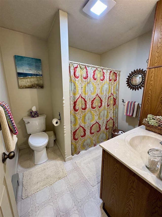 bathroom featuring vanity, toilet, tile patterned flooring, and a textured ceiling