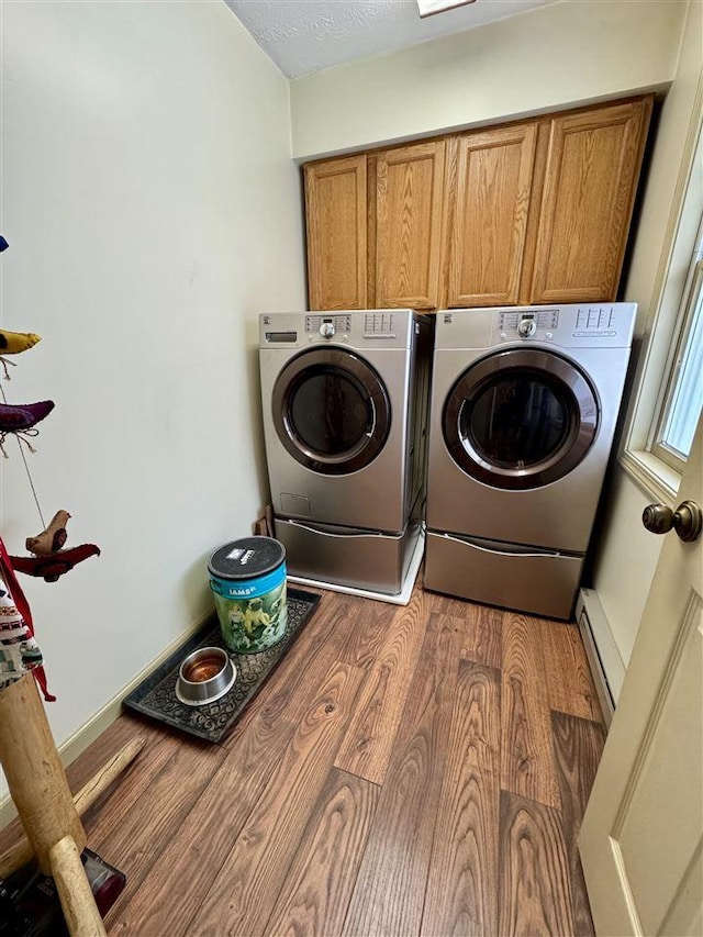 clothes washing area featuring dark hardwood / wood-style flooring, independent washer and dryer, a baseboard radiator, and cabinets