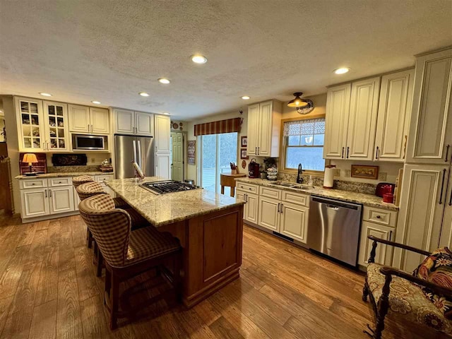 kitchen featuring hardwood / wood-style flooring, appliances with stainless steel finishes, sink, and a center island with sink