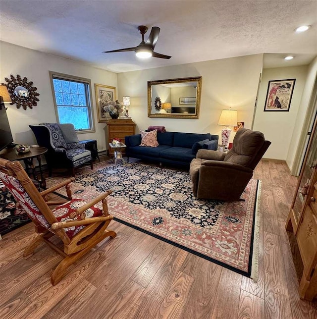 living room featuring ceiling fan, a textured ceiling, and light wood-type flooring