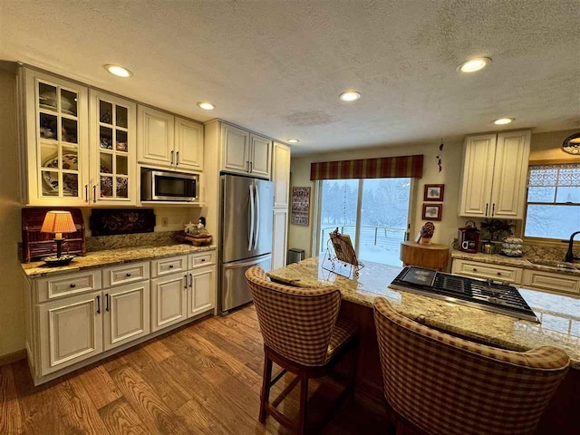 kitchen with light stone countertops, a wealth of natural light, stainless steel appliances, and light wood-type flooring