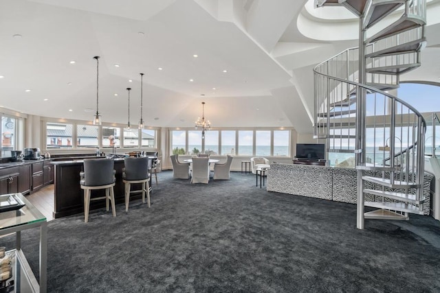 carpeted living room with a notable chandelier and high vaulted ceiling