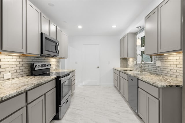 kitchen featuring stainless steel appliances, sink, light stone counters, and gray cabinets