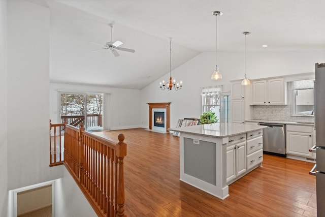 kitchen with white cabinetry, a center island, light hardwood / wood-style flooring, stainless steel dishwasher, and pendant lighting