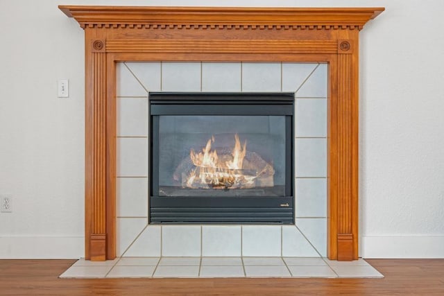 interior details featuring hardwood / wood-style flooring and a tiled fireplace