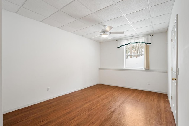 empty room featuring hardwood / wood-style flooring, a drop ceiling, and ceiling fan