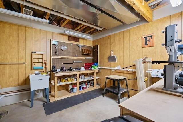 basement with wooden walls and a workshop area