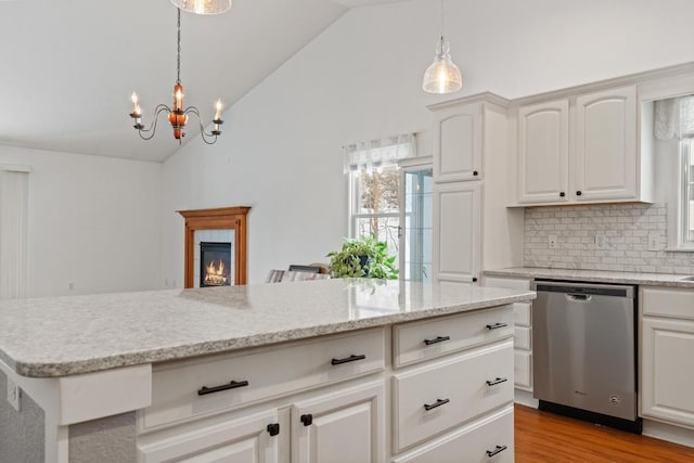 kitchen featuring a tiled fireplace, stainless steel dishwasher, white cabinets, and decorative light fixtures