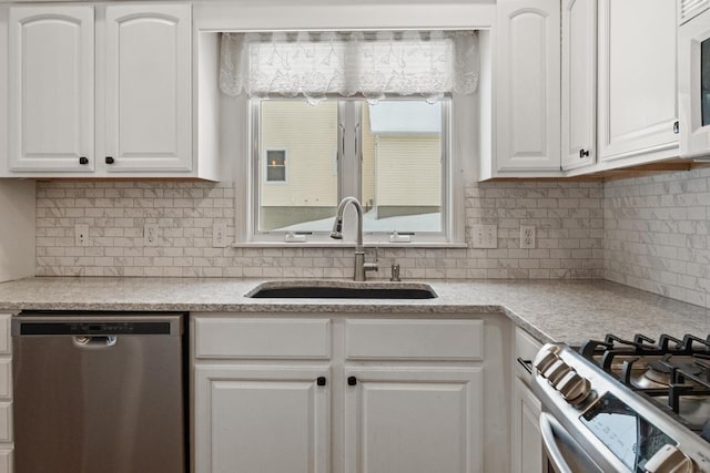 kitchen featuring tasteful backsplash, stainless steel dishwasher, sink, and white cabinets