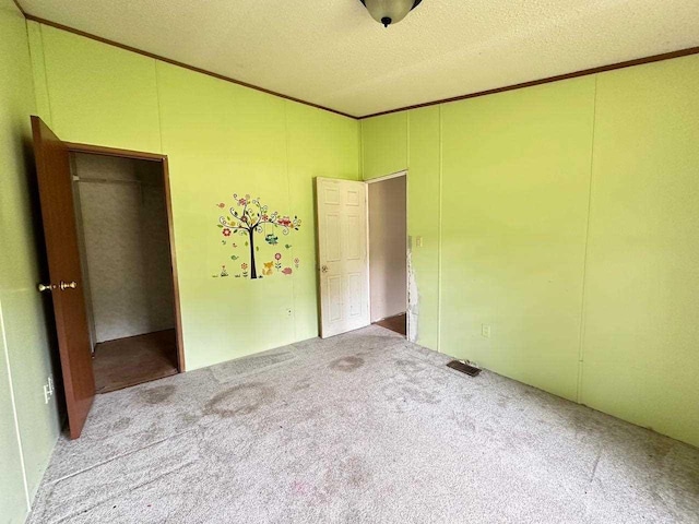 unfurnished bedroom featuring ornamental molding, light carpet, and a textured ceiling