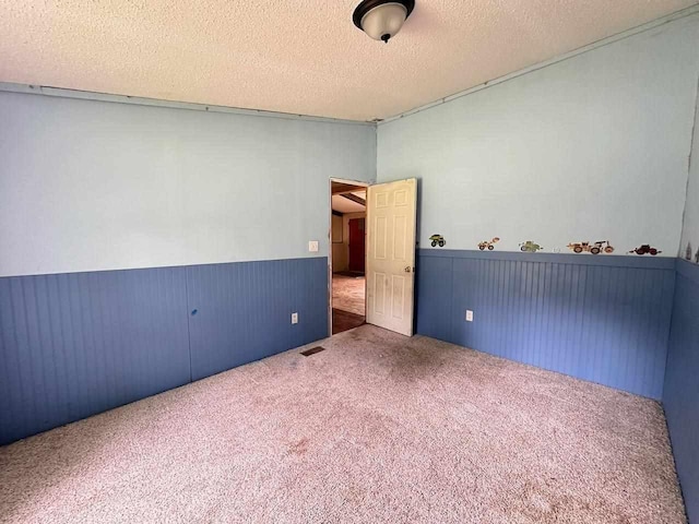 carpeted empty room with a textured ceiling