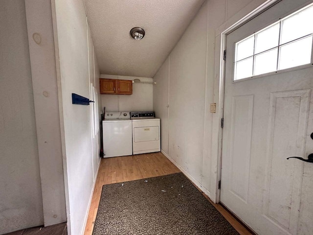 washroom featuring cabinets, washer and clothes dryer, a textured ceiling, and light wood-type flooring