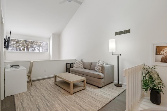 living room with high vaulted ceiling, radiator heating unit, and light hardwood / wood-style floors