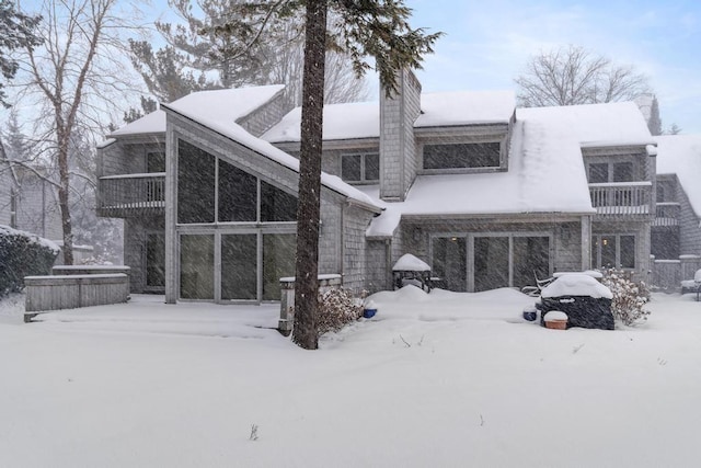 snow covered back of property with a balcony