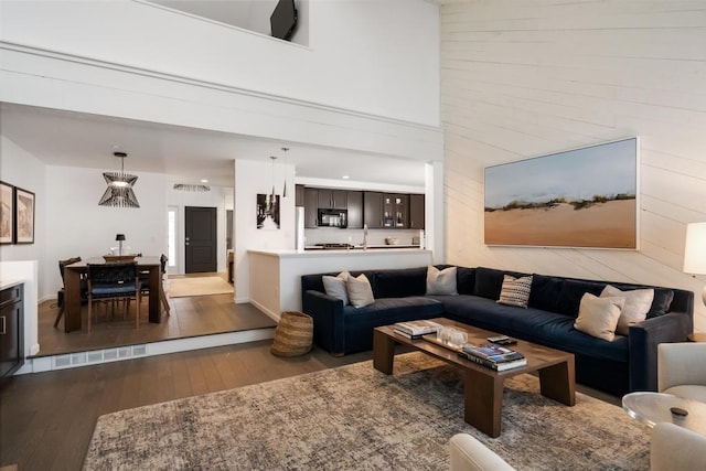 living room with a high ceiling, wooden walls, and light wood-type flooring