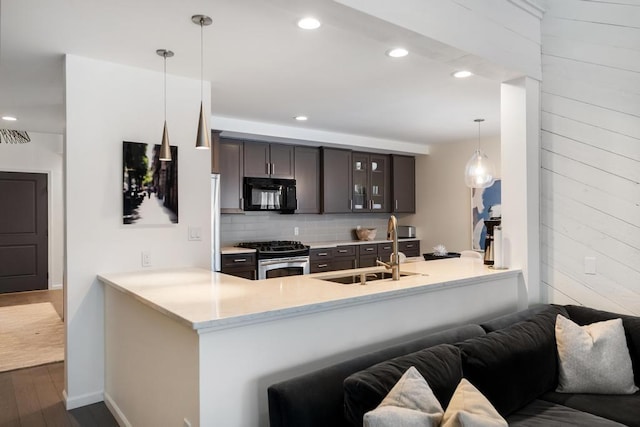 kitchen featuring dark wood-type flooring, dark brown cabinetry, decorative light fixtures, stainless steel range with gas cooktop, and kitchen peninsula