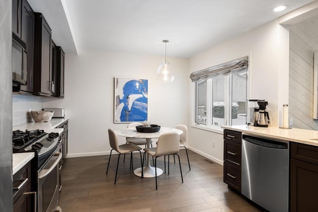 kitchen with dark hardwood / wood-style flooring, hanging light fixtures, decorative backsplash, and appliances with stainless steel finishes