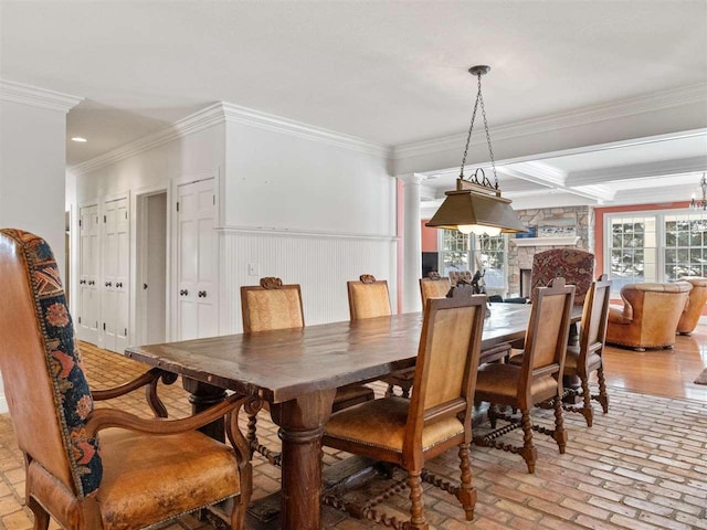 dining space featuring beam ceiling, crown molding, and a stone fireplace