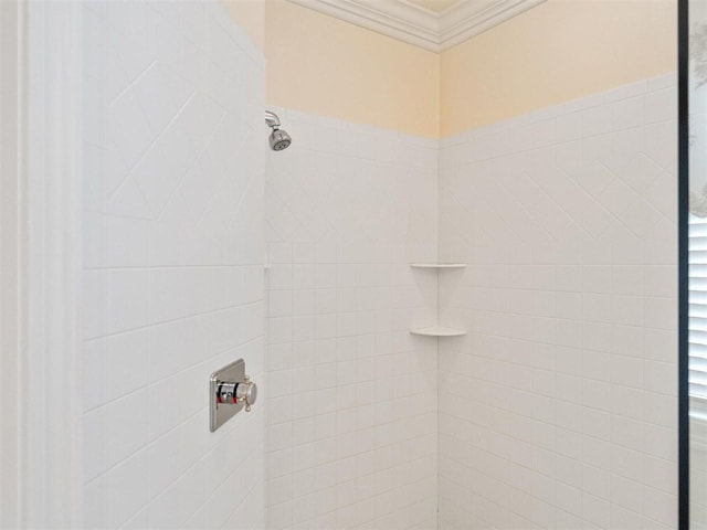 bathroom with a tile shower and ornamental molding