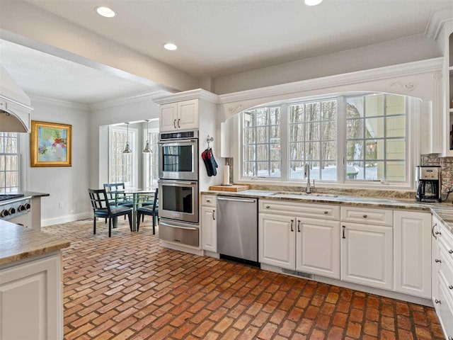 kitchen featuring appliances with stainless steel finishes, white cabinetry, sink, decorative backsplash, and ornamental molding