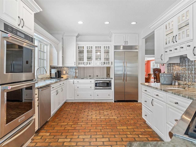 kitchen featuring white cabinetry, built in appliances, and sink