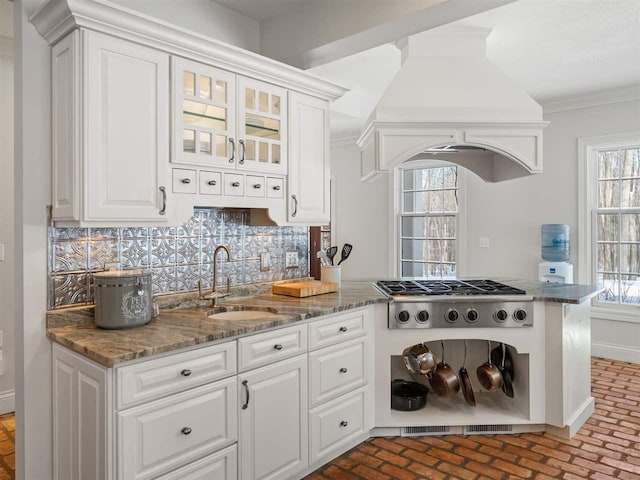 kitchen featuring sink, white cabinetry, ornamental molding, custom range hood, and decorative backsplash