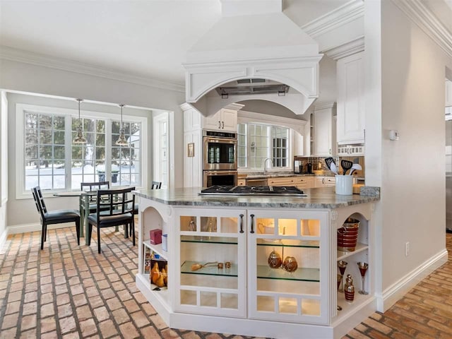 kitchen featuring tasteful backsplash, white cabinets, dark stone counters, ornamental molding, and stainless steel appliances