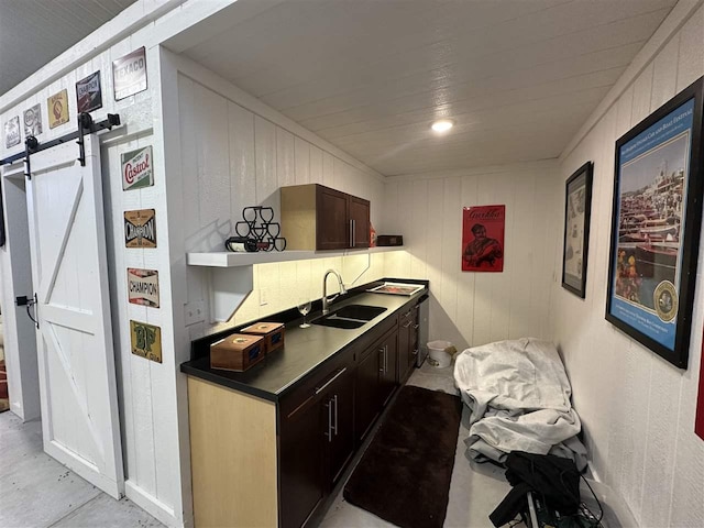 kitchen with dark brown cabinetry, a barn door, and sink